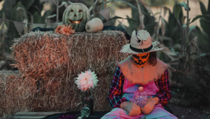 Una chica disfrazada de espantapájaros, rodeada de calabazas de Halloween