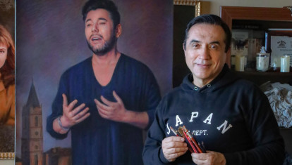 El artista malagueño, pinceles en mano, posa junto a uno de sus retratos