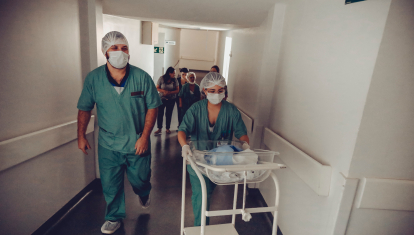 Una matrona llevando a un bebé recién nacido por un hospital
