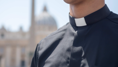 Un sacerdote con la basílica de San Pedro de fondo