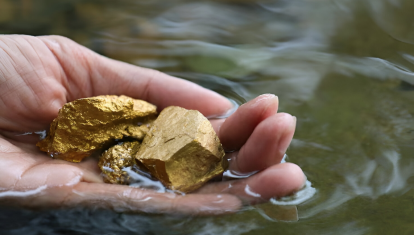 Primer plano de una mano sosteniendo oro en un río