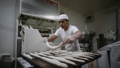 Un trabajador prepara barras de pan en un obrador