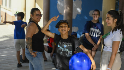 Un niño beneficiario del programa CaixaProinfancia sonríe a cámara sujetando una pelota