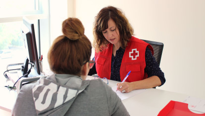 Voluntaria de Cruz Roja atendiendo a una demandante