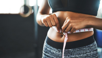 Cropped shot of a fit young woman measuring her waist in a gym