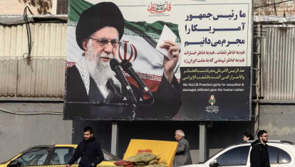 Los iraníes pasan junto a una valla publicitaria que muestra al líder supremo iraní, el ayatolá Ali Khamenei, con retórica antiestadounidense en Teherán
