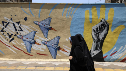 Mujeres iraníes pasan junto a un mural antiestadounidense y antiisraelí en Teherán