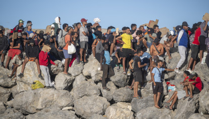 Miembros de la Cruz Roja reparten comida a los inmigrantes en una playa, a 21 de agosto de 2026