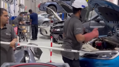 Imagen de un mecánico sostenido por la pértiga de seguridad arreglando un eléctrico