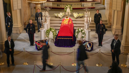 Los dolientes desfilan silenciosamente frente al féretro del rey después de que se abriera la fila para el velatorio el martes por la tarde.