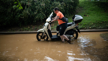 Una mujer empujando su moto en un barrio de Barcelona debido a las inundaciones