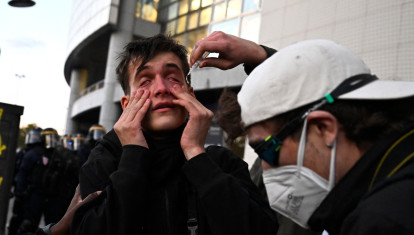 Un manifestante intenta lavarse los ojos tras haber sido expuesto a gases lacrimógenos durante una protesta de estudiantes de secundaria en la plaza de la Bastilla, en París