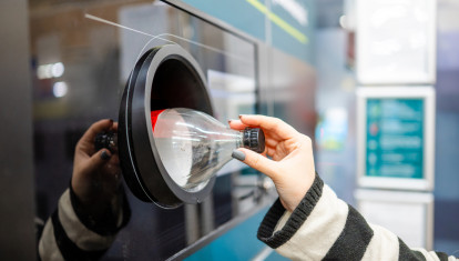 Una mujer devuelve una botella de refresco en una máquina habilitada para ello