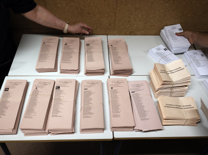 Varios responsables de mesa colocan las papeletas electorales sobre una mesa