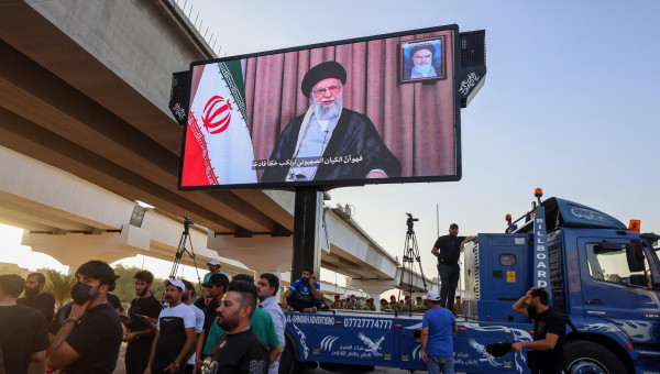Partidarios de grupos iraquíes proiraníes exhiben una pantalla con el líder supremo de Irán, el ayatolá Alí Jamenei
