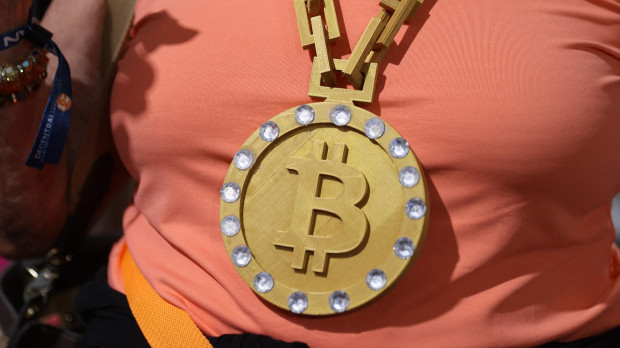 Una mujer lleva una medalla con el símbolo del bitcoin en una convención de criptomonedas