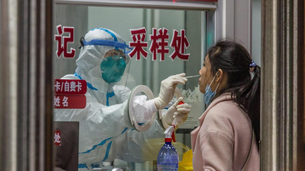 Un sanitario realiza una PCR a una mujer en China