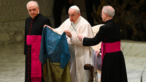 El Santo Padre sujeta una bandera de Ucrania traída de Bucha durante la audiencia general de este miércoles