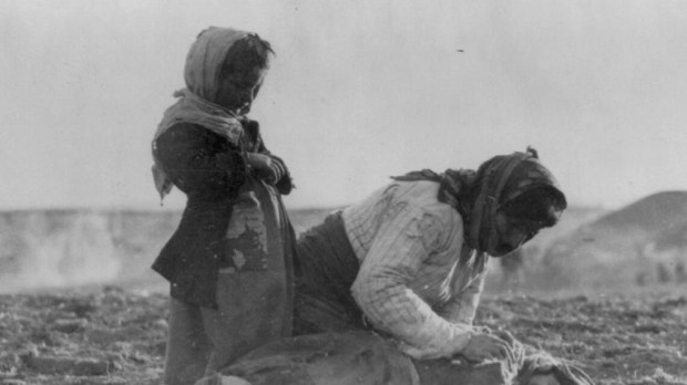 Una mujer armenia arrodillada junto a un niño muerto en el campo