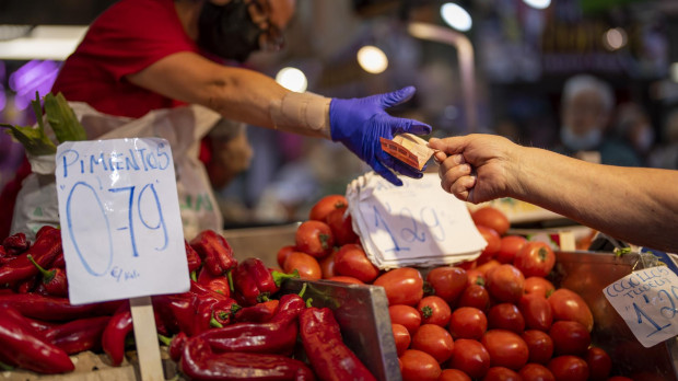 Un consumidor paga en un puesto de hortalizas del Mercado de Maravillas de Madrid