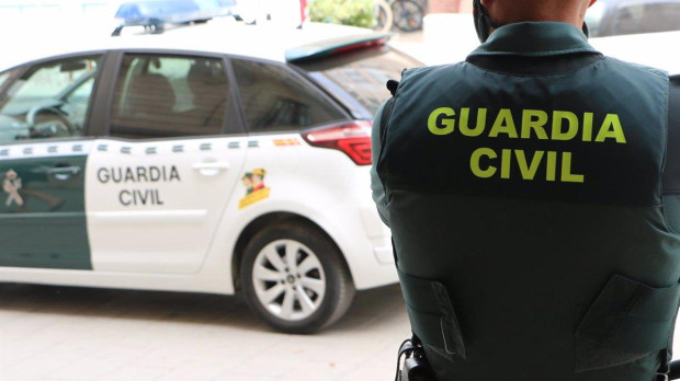 Un agente de la Guardia Civil junto a un coche patrulla