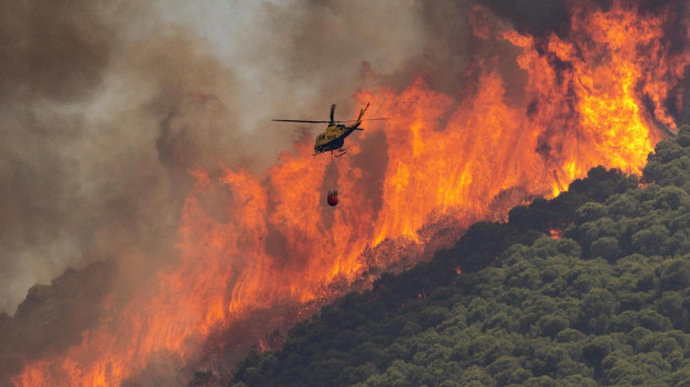 Un helicóptero trabaja en la extinción del incendio del paraje El Higuerón de Mijas