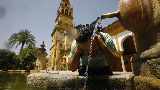 Un turista se refresca en una de las fuentes del patio de los naranjos de la Mezquita de Córdoba, en julio