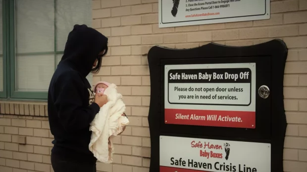 Una mujer con su bebé, frente a una caja refugio de Safe Haven