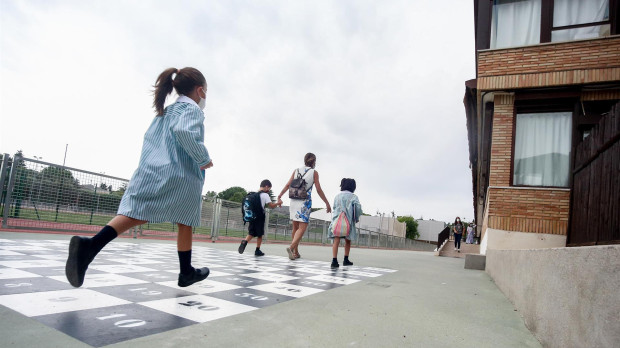 Una madre acompaña a sus hijos a la entrada del colegio.