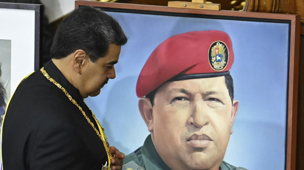 Nicolás Maduro, pasa junto a un retrato del difunto presidente Hugo Chávez mientras presenta su informe anual a la Asamblea Nacional en Caracas