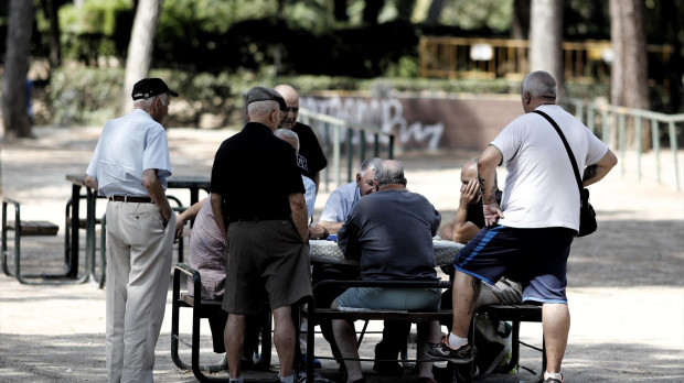 Varios pensionistas juegan al dominó en un parque de Madrid.