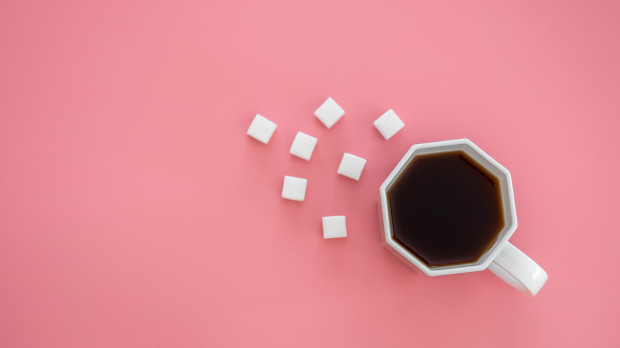 Taza de café acompañada de edulcorantes