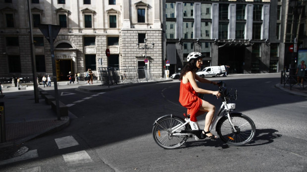 Una ciclista pasea con una bicicleta eléctrica cerca del Congreso de los Diputados.