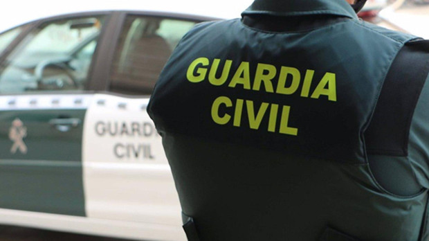 Un agente de la Guardia Civil, de espaldas, junto a un vehículo oficial