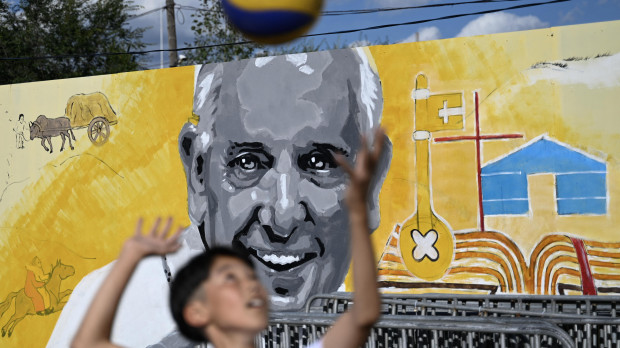 A boy plays in front of a mural of Pope Francis outside Sts. Peter and Paul Catholic Cathedral in Ulaanbaatar on August 31, 2023. Pope Francis is set to visit Mongolia and tour the Buddhist-majority nation's capital at the government's invitation this week, becoming the first pontiff to set foot there. (Photo by Pedro PARDO / AFP)