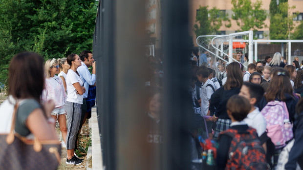 Padres miran a sus hijos a través de la verja del colegio