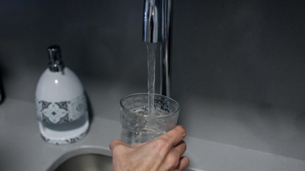 Una persona llena un vaso de agua de un grifo