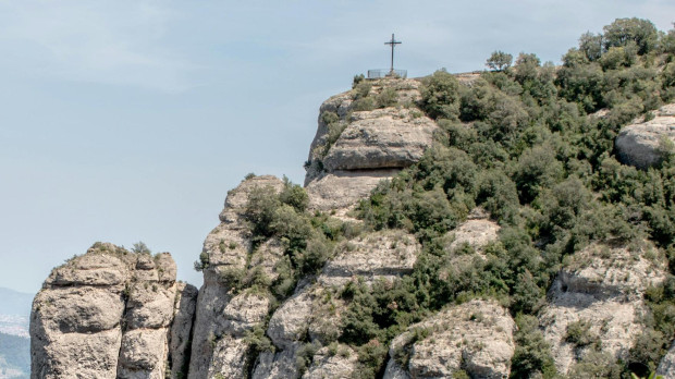 Una cruz corona una cima en la montaña de Montserrat, en Cataluña