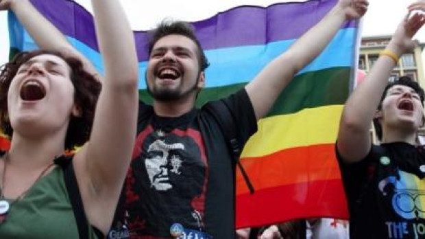 Un manifestante con la bandera arco iris y una camiseta con la imagen del Che Guevara