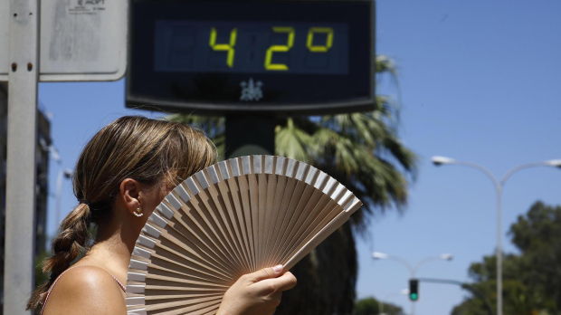 Una mujer se abanica mientras pasa por un termómetro de calle que marca 42 grados n Córdoba