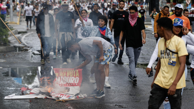 Numerosas personas recorren las calles quemando carteles del presidente reelecto de Venezuela, Nicolás Maduro