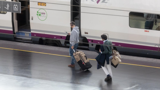 Varios viajeros cogen un tren en la Estación Puerta de Atocha-Almudena Grandes.