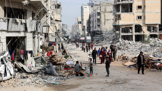 La gente camina entre los escombros de los edificios derrumbados y dañados a lo largo de una calle en la ciudad de Gaza