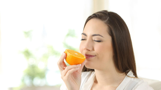 Woman smelling half orange at home