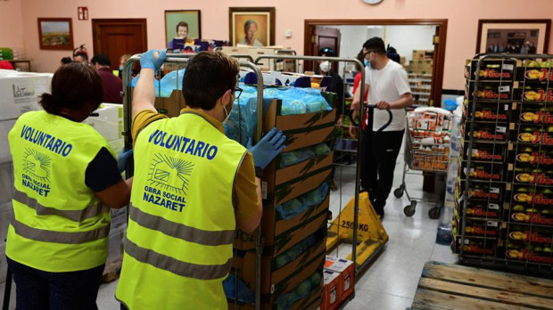Varios voluntarios preparan lotes de alimentos para personas necesitadas en la sede de la obra social Nazaret, en el barrio obrero de San Blas