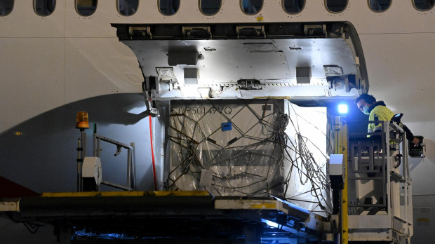 Trabajadores del aeropuerto bajando los palés de recogen la vacuna Moderna