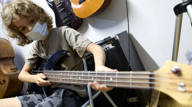 Un niño tocando el bajo en un campamento urbano artístico en Madrid