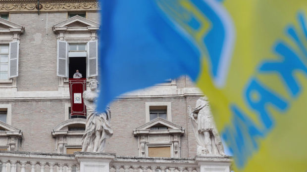 El Santo Padre asomado a la ventana del palacio apostólico con una bandera de Ucrania al frente