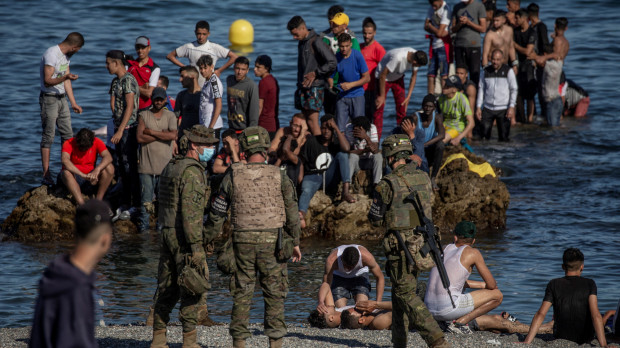 Soldados del Ejército de Tierra observan como un grupo de inmigrantes alcanzan la playa fronteriza de El Tarajal de Ceuta
