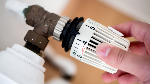 Un hombre baja la temperatura de la calefacción en su vivienda